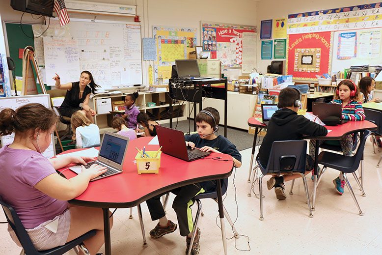 Teacher Lei Han Hong, left, leads a small group of Normandy Park Elementary School students in traditional learning, while others work individually on their laptops.