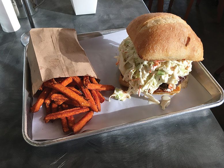 The Que, a burger topped with pulled pork, brisket, coleslaw and smoked Gouda.