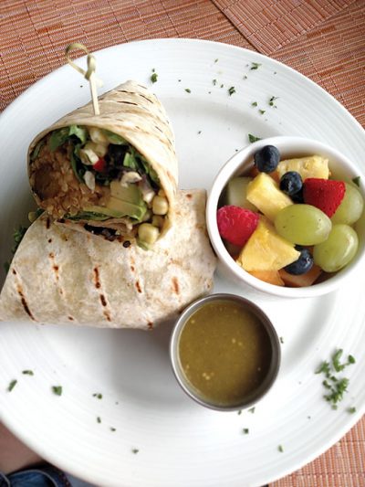 The vegan burrito , stuffed with plantains and served with avocado, black-bean-and-corn salsa, tomatillo sauce and a side of fruit salad.