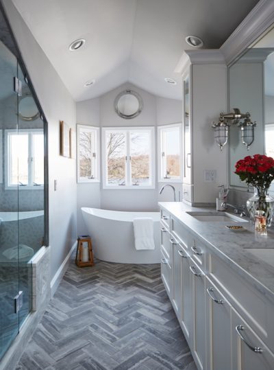 Designer Anthony Passanante conceived his new master bathroom to take advantage of the lake views, leaving the windows unadorned. Accessories are nautical, including the sconces and porthole mirror.