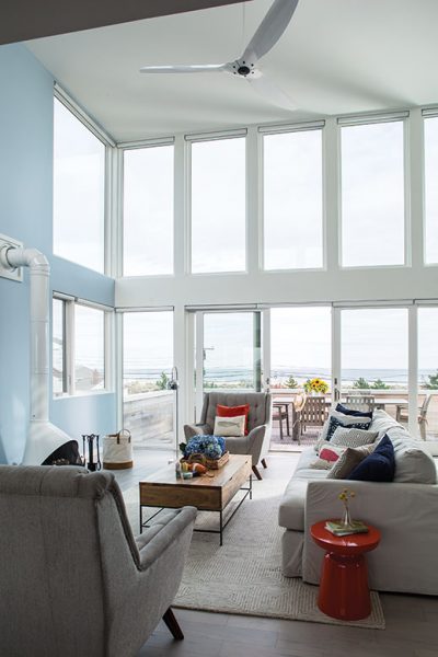 The main living area features a wall of windows looking out toward the beach.