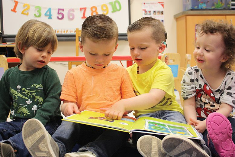Children reading a picture book together in one of the three Sound Start Babies nursery rooms.