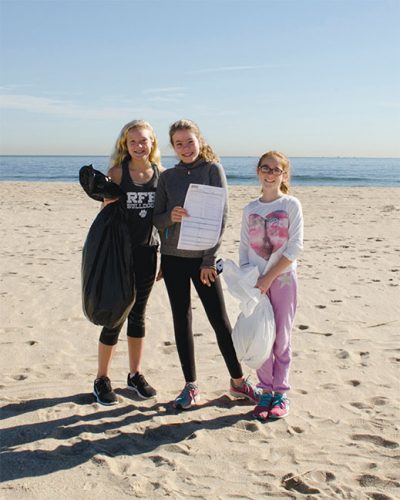 A trio of young volunteers filled a black bag with garbage and a white bag with recyclables at Clean Ocean Action's fall 2017 Beach Sweeps in Sea Bright. The card is used to record data.