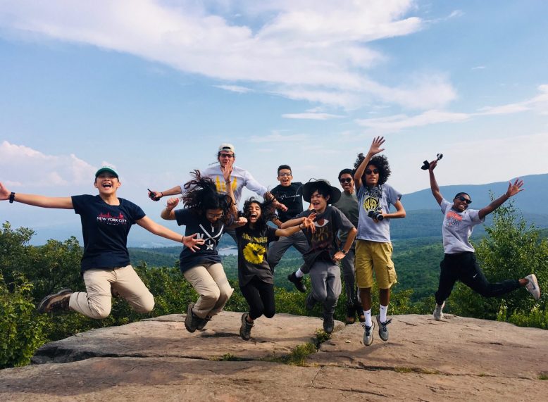 Students jump into the air at the top of a hike.