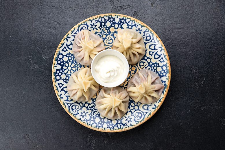 Georgian dumplings with sour cream on blue plate