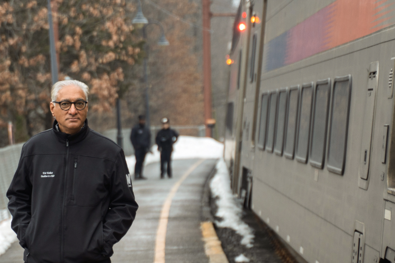 Kris Kolluri beside an NJ Transit train
