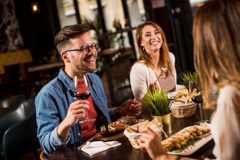 Group of happy young people having dinner in the restaurant